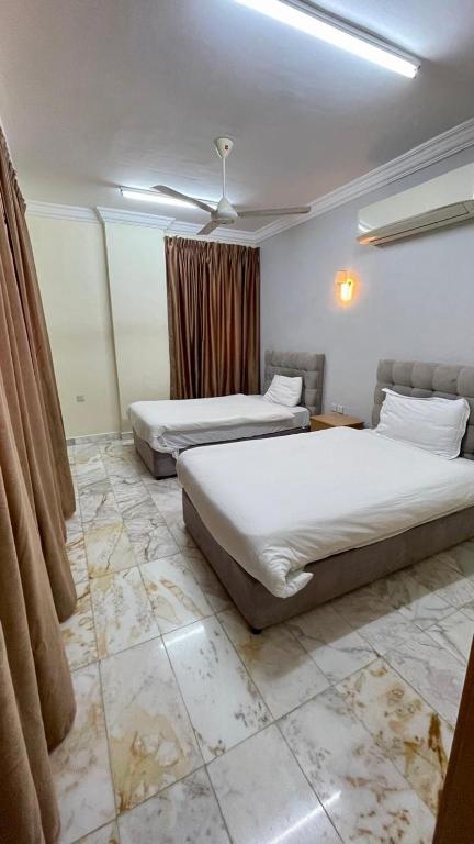a bedroom with two beds and a ceiling fan at البرق للشقق المفروشة in Salalah
