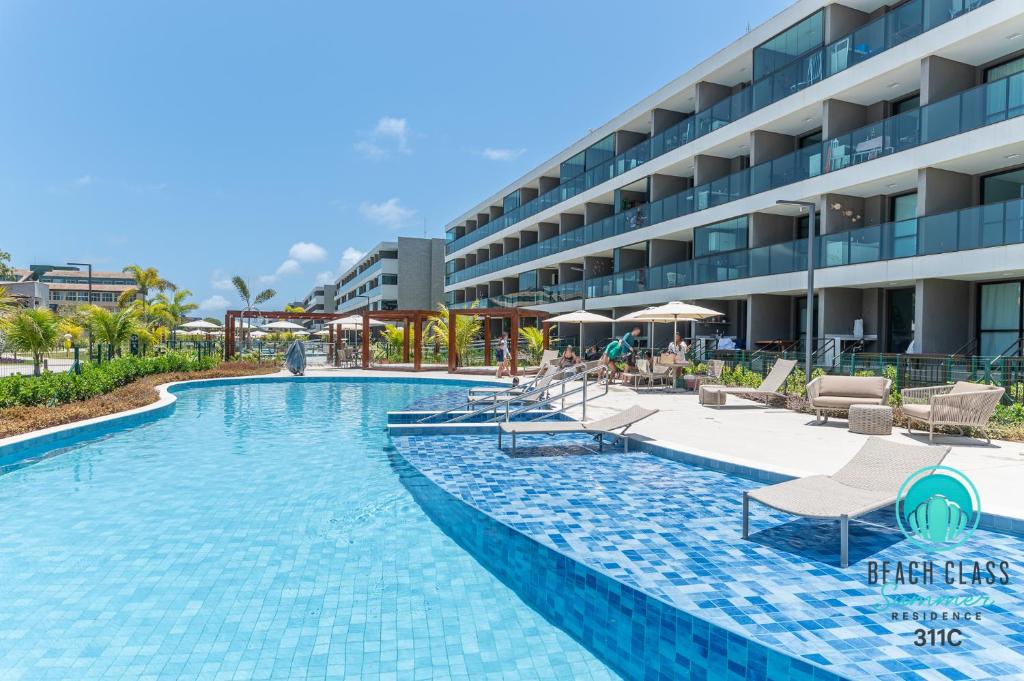 Refúgio Verão - Flat de alto padrão na praia do Cupe - Porto de Galinhas في بورتو دي غالينهاس: مسبح وكراسي وفندق