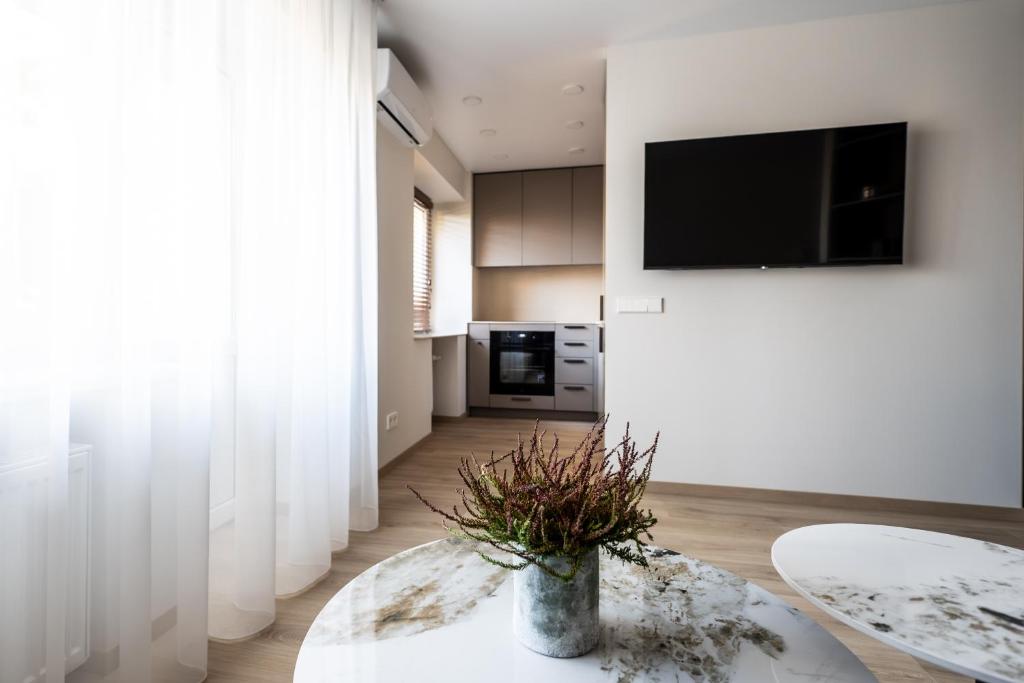 a living room with a table and a tv on a wall at Vytauto 12 in Marijampolė