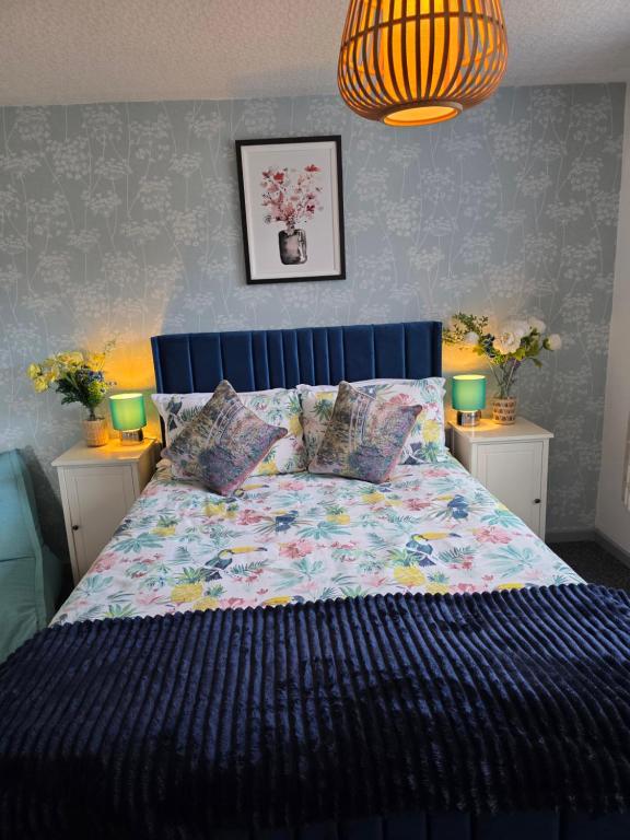 a bedroom with a bed with a blue head board at Charming 2 Bed Modern Guest House with Free Parking up to 3 cars in Beeston