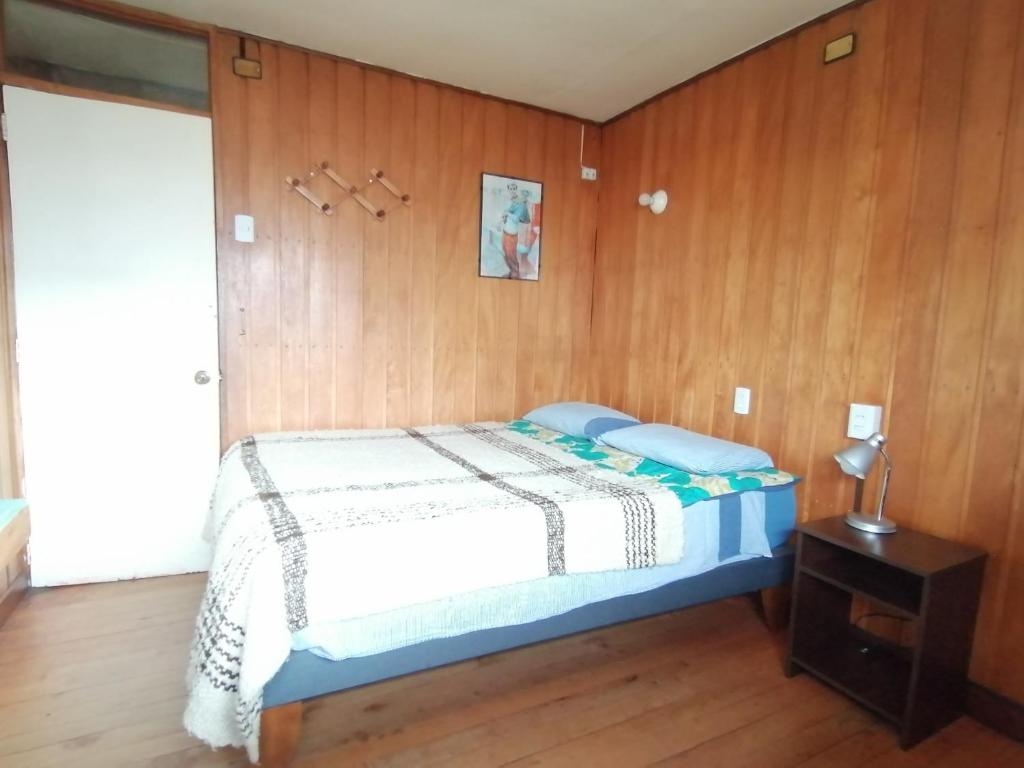 a bedroom with a bed and a wooden wall at Habitación privada en Puerto Varas in Puerto Varas