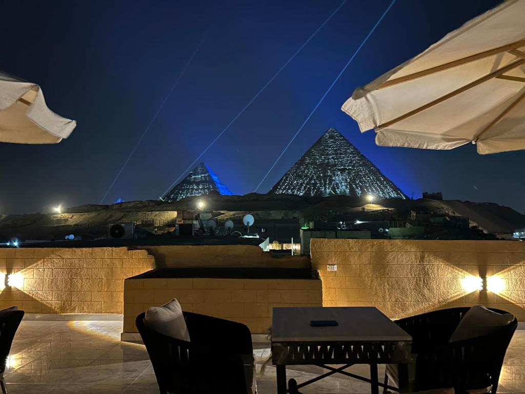 a table and chairs on a rooftop at night at Alex Pyramids View Inn in Giza