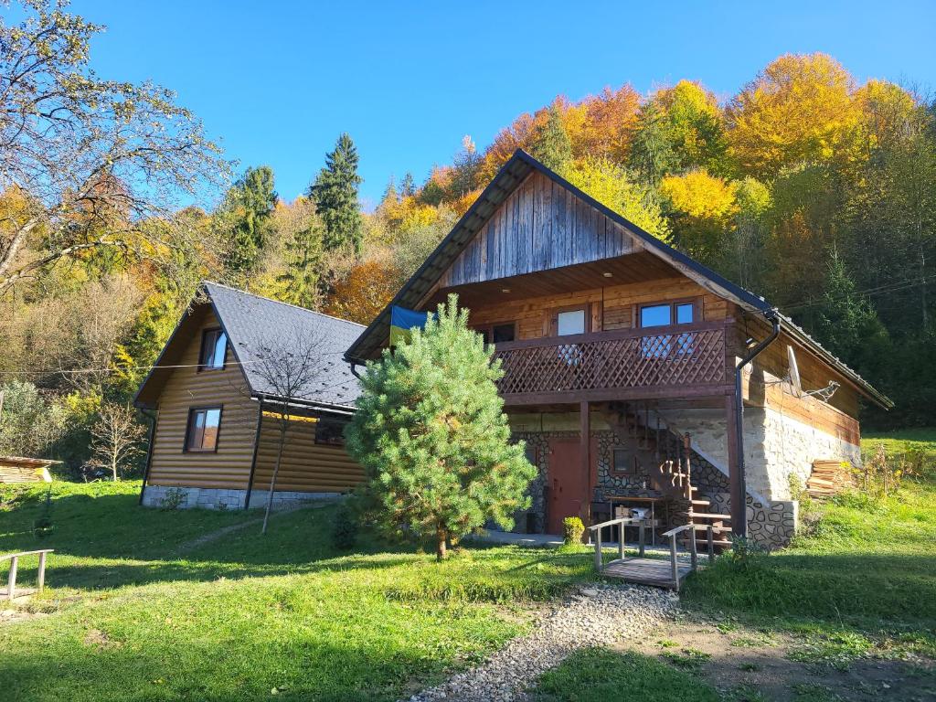a wooden house with a tree in front of it at Під горою 2 in Sheshory