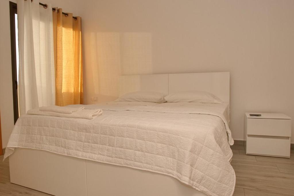 una camera bianca con un letto bianco e una coperta di Comfort and Peace a Santa Maria