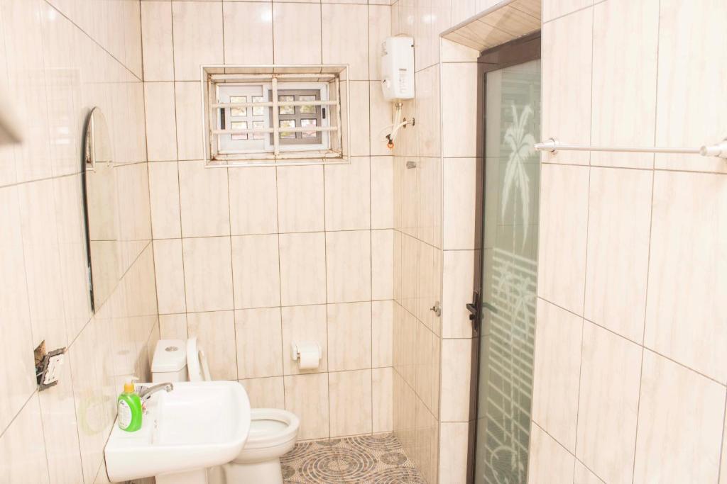 ein Badezimmer mit Toilette, Waschbecken und Dusche in der Unterkunft 2Bedroom Apartment at Pokuase in Ayaso