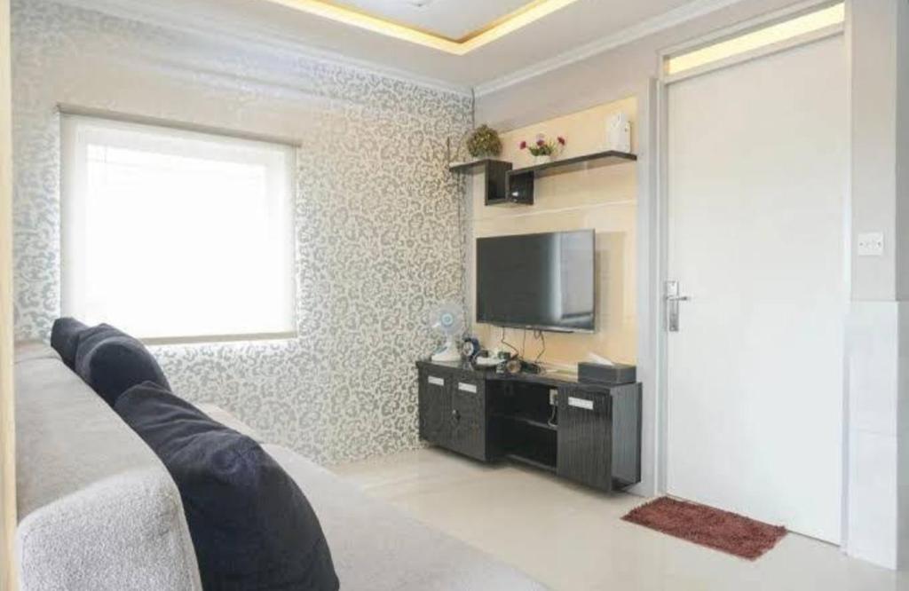 a bedroom with a bed and a tv and a window at Menteng Square Sahara II in Jakarta