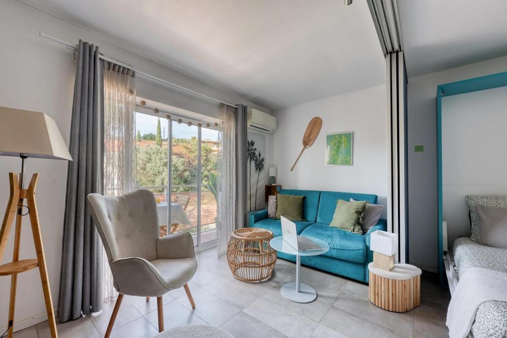 Una sala de estar con un sofá azul y una ventana. en Escapade à Bandol balcon verdoyant et plage à deux pas, en Bandol