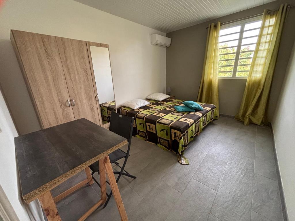 a small room with a bed and a table at Chambre zen & bien-être à 5 mn de la Galléria in Le Lamentin