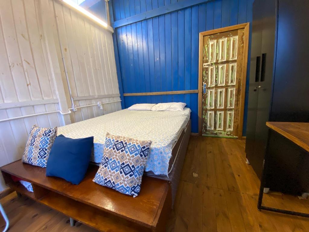 een slaapkamer met een bed met blauwe muren en een deur bij Cabana da palmeira in Piçarras
