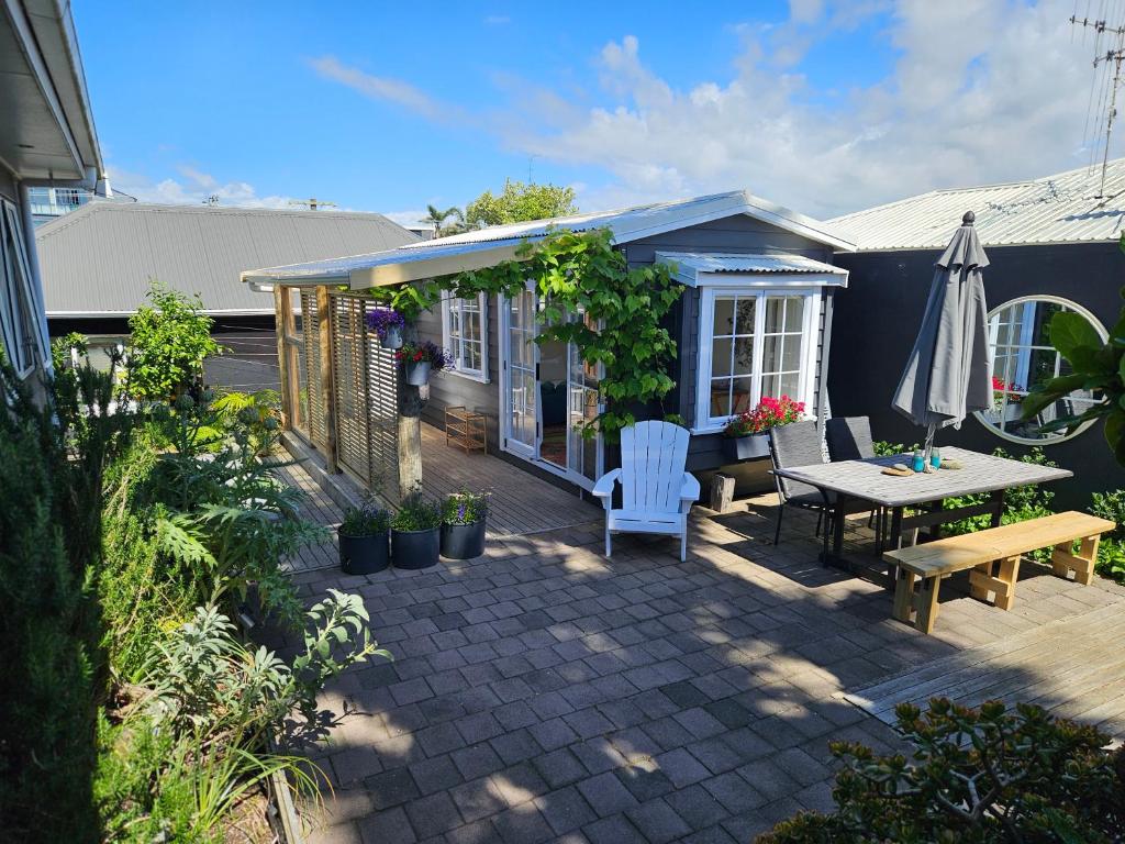 a patio with a table and chairs and an umbrella at Zen Cabin in Mount Maunganui