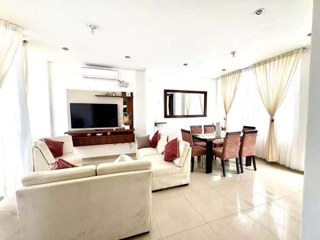 a living room with white furniture and a dining room at Apartamento de lujo en Piura in Piura
