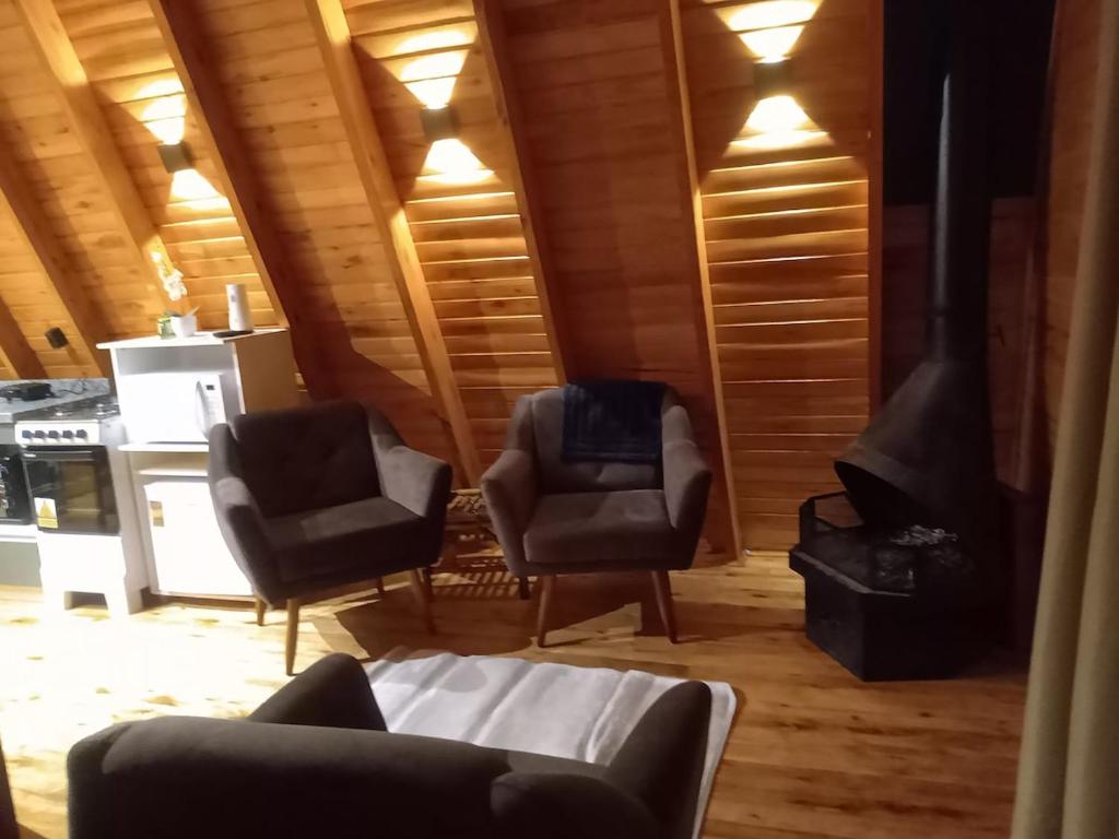 a living room with two chairs and a stove at Cabana Encanto da Mata in Santa Maria do Erval