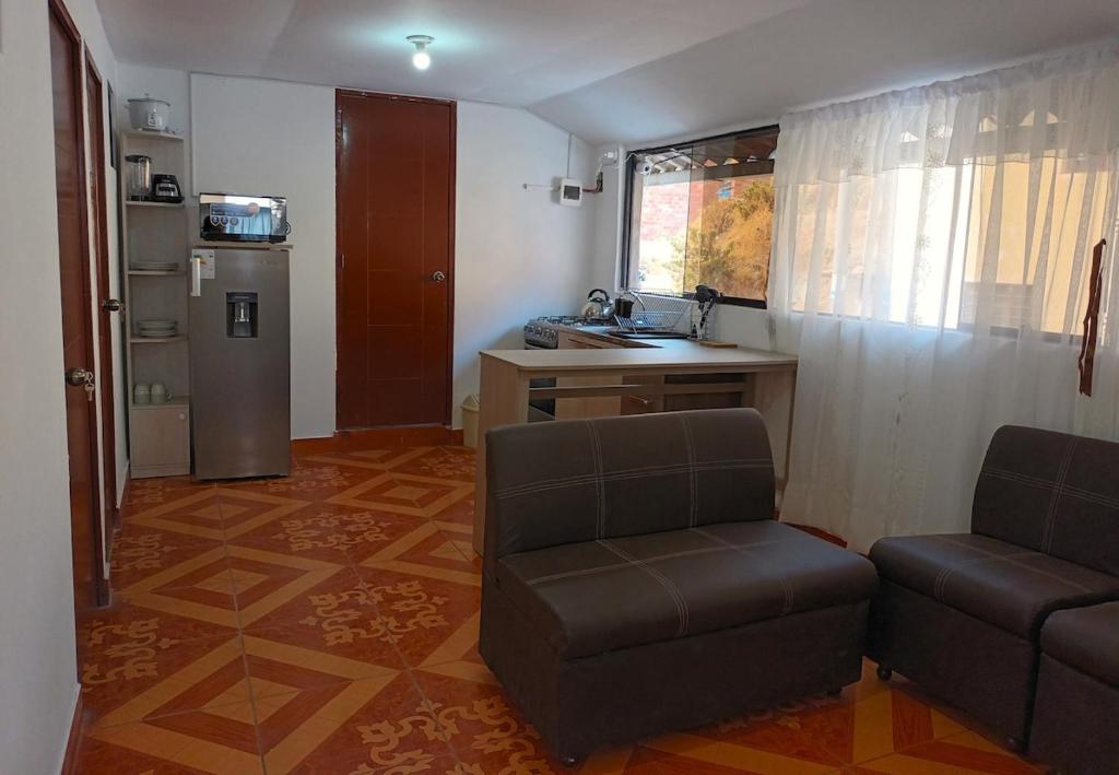a living room with a couch and a chair and a kitchen at Sumaq Tika in Cusco