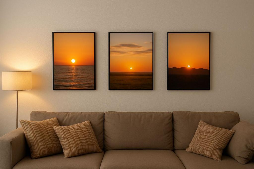 a living room with four paintings of the sunset at SH Apartments in Hannover