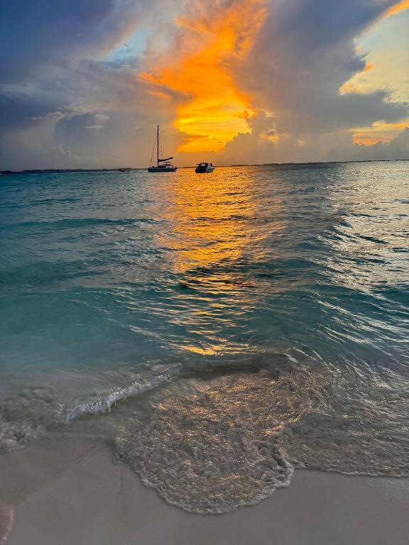 a boat in the water on the beach at sunset at Condo Lux Xareni in Playa del Carmen