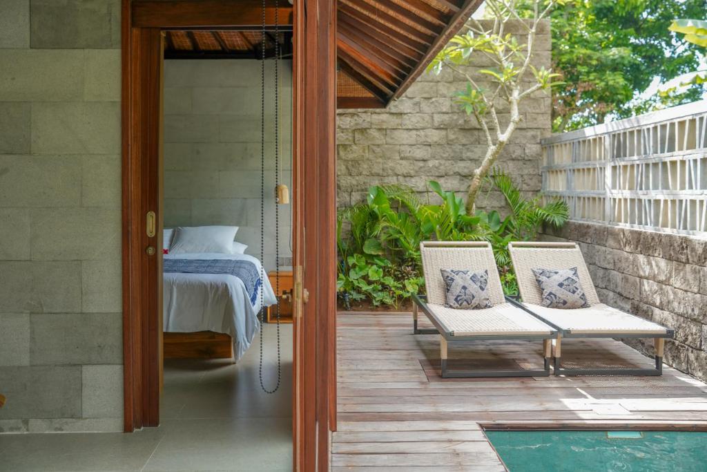 Jumah Bingin by Melali - private villas في Bingin Beach: فناء على كرسيين وسرير على شرفة
