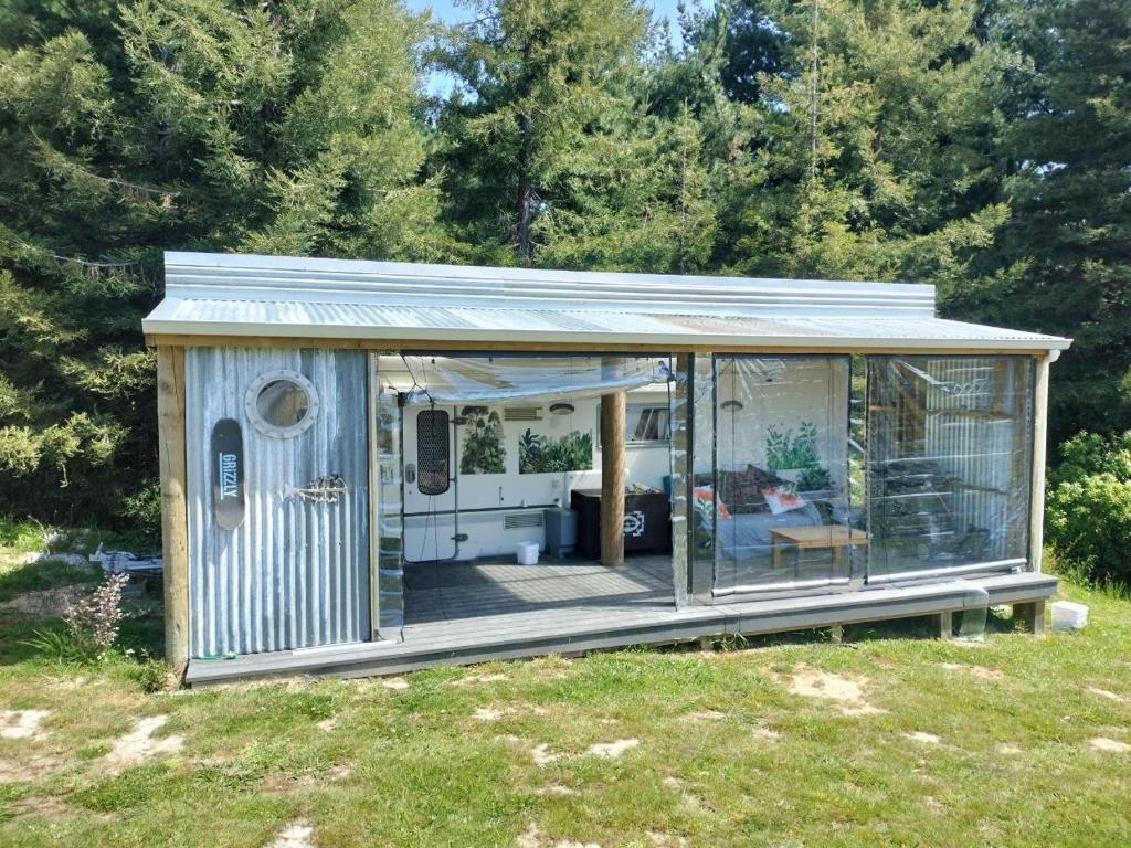 a small shed with a deck in a field at Redwood Valley B and B Caravan Retreat in Redwoods Valley