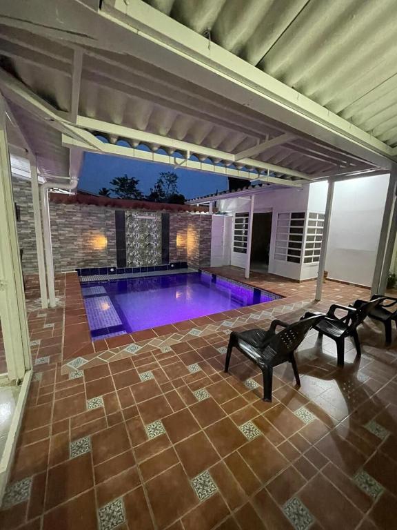 a swimming pool with two black benches in front of it at Casa vacacional El Oasis in Villavicencio