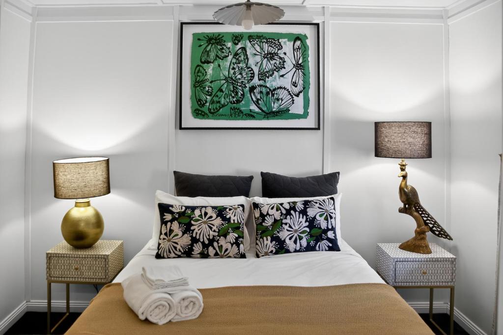 ein Schlafzimmer mit einem Bett mit zwei Nachttischen und zwei Lampen in der Unterkunft Cedar Cottage Daylesford in Daylesford