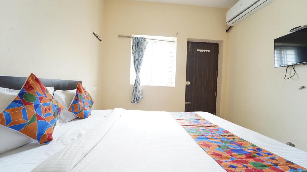 a bedroom with a large white bed with colorful pillows at Aangal residency in Coimbatore
