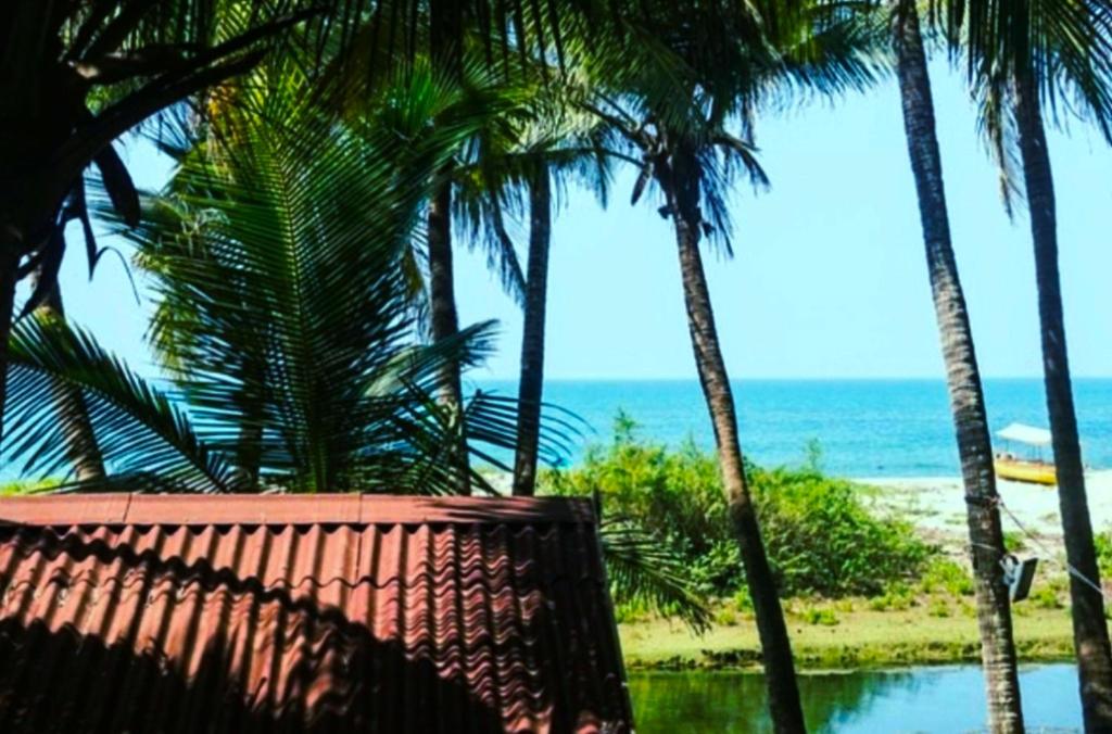 a view of a beach with palm trees and the ocean at Samant Beach Resort in Malvan