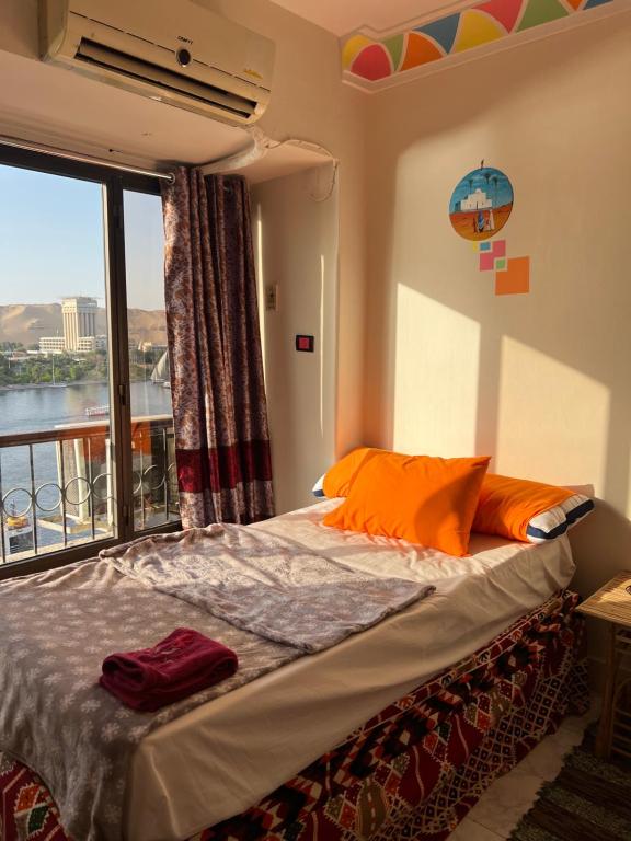 a bedroom with a bed and a large window at NubaNest GuestHouse in Aswan