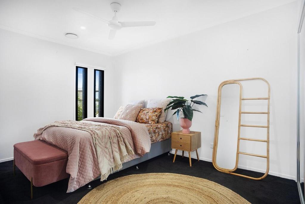 a bedroom with a bed with a pink blanket and a ladder at Syldah Stay Mango Hills in North Lakes