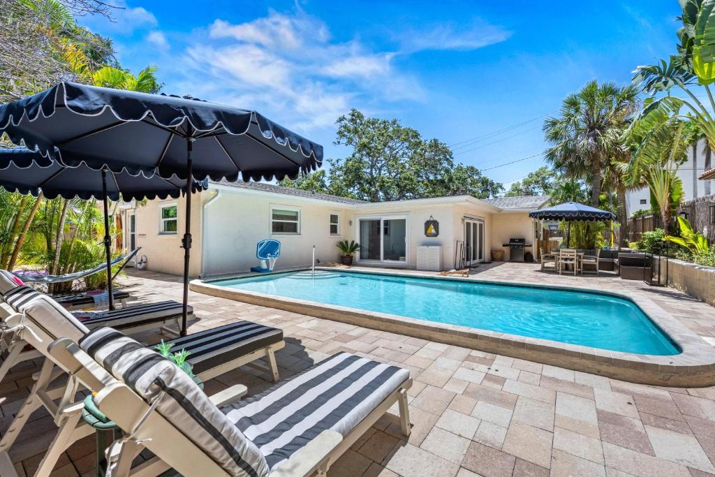 a pool with two chairs and an umbrella next to a house at Siesta Dolce - 3750 in Siesta Key