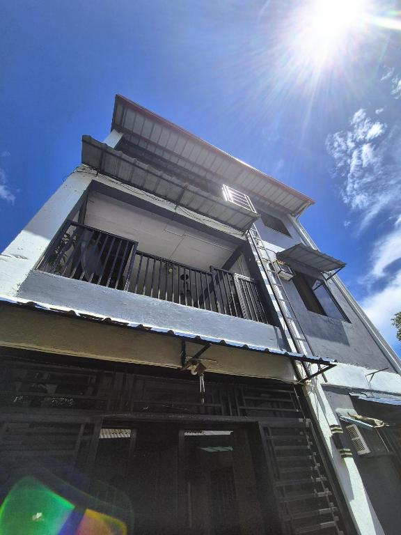 a building with a balcony with the sun in the sky at 88 Tourist Inn by Lagum Adventure in Coron