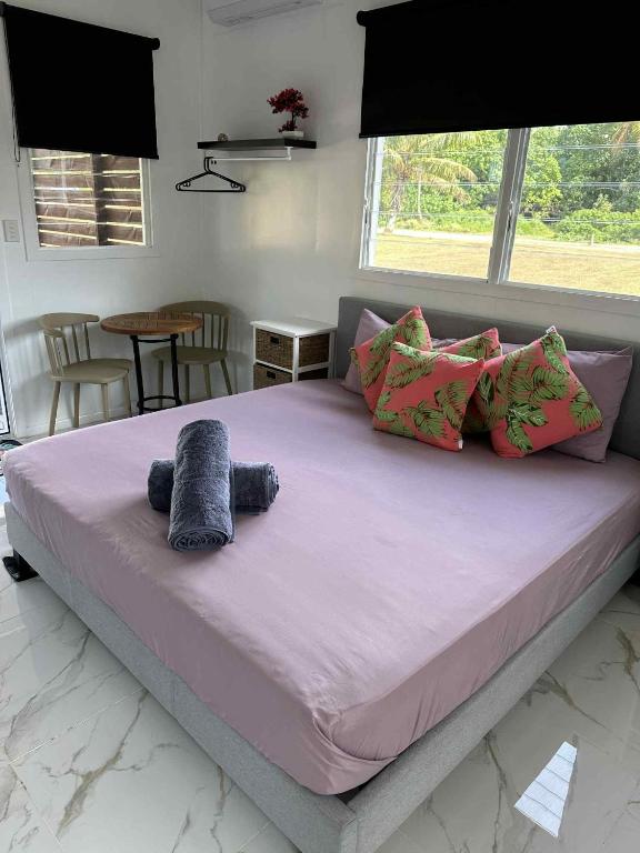 a bedroom with a large bed with purple sheets and pillows at Sharnyta's Studio Aitutaki in Amuri