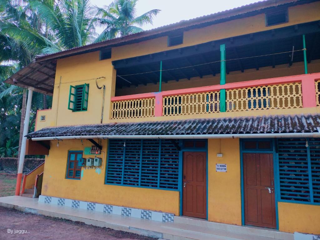 una casa amarilla con puertas rojas y palmeras en Totadamane in murdeshwar, en Bhatkal