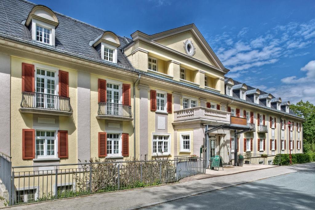 un grand bâtiment jaune avec volets rouges dans une rue dans l'établissement Santé Royale Hotel- & Gesundheitsresort Bad Brambach, à Bad Brambach