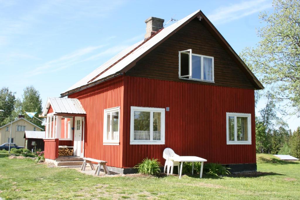 a red house with a white chair in front of it at Lillvikens Gästhuset och Stugor in Nedre Lillviken