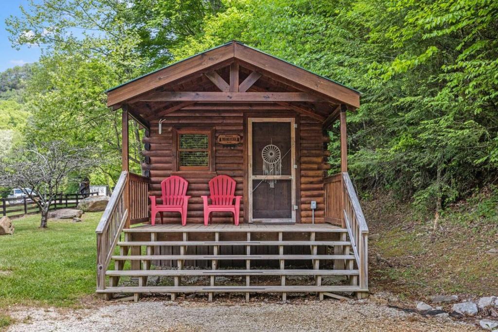 two red chairs sitting on the porch of a log cabin at WiFi - Dreamcatcher - Lux-Tiny Cabin in RRG KY in Rogers