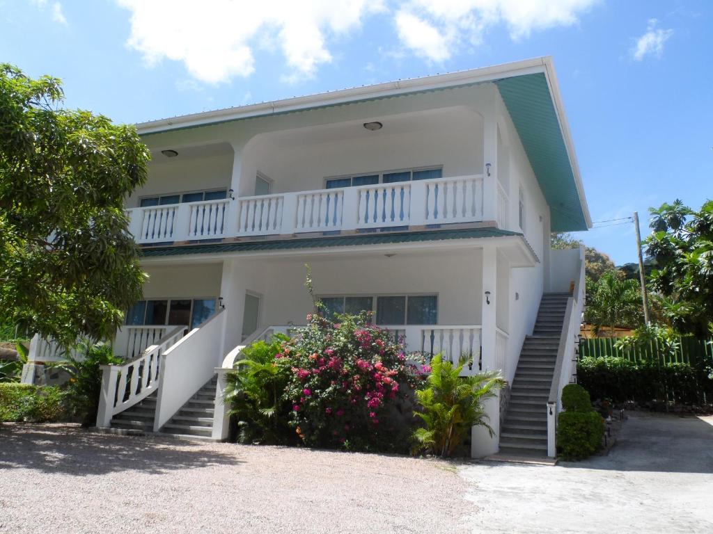 a large white house with stairs and flowers at Divers Lodge Guest House in Beau Vallon