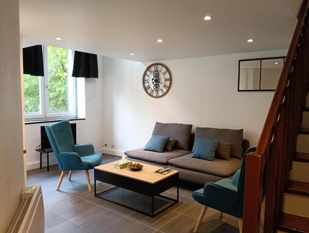 a living room with a couch and chairs and a clock at Le duplex d'Abi in Saint-Étienne