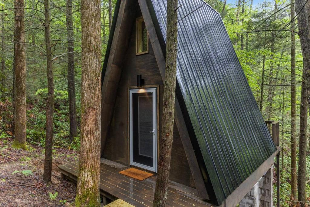 a small cabin in the woods with a black roof at The Overlook - Camping Cabin Retreat in RRG KY in Rogers