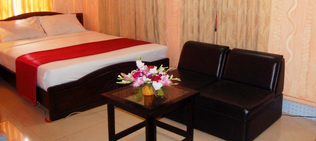 ein Schlafzimmer mit einem Bett, einem Stuhl und einem Tisch in der Unterkunft Hotel Swiss Garden International in Chittagong