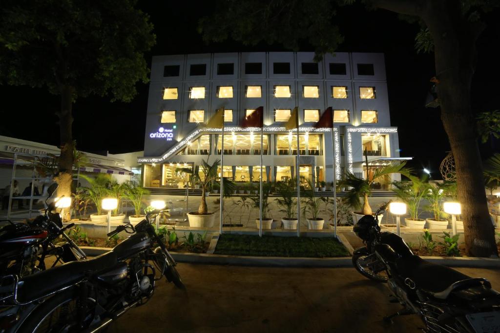a hotel with motorcycles parked in front of it at night at Hotel Arizona Inn in Anand