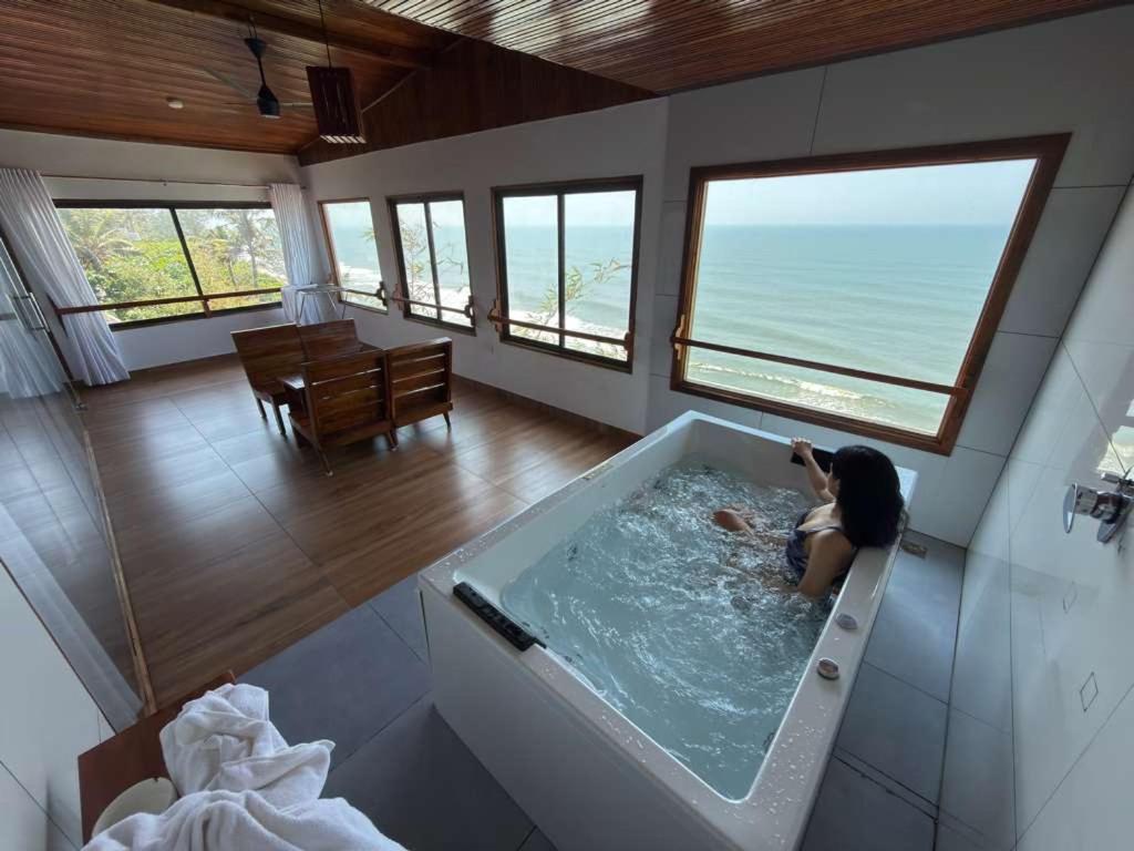 eine Frau, die in einer Badewanne in einem Zimmer sitzt in der Unterkunft Peak Paradise Resort in Varkala