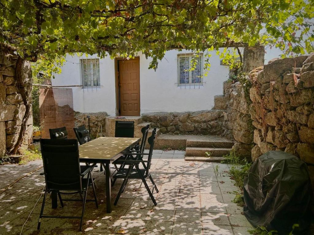 にあるCasa con parra de uva y pazの石壁の下に座るテーブルと椅子