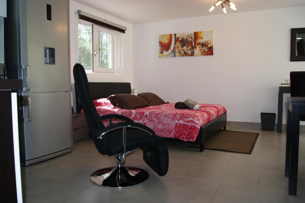 a bedroom with a bed and a black chair at Studio d'hôtes Villa Castelnau in Castelnau-le-Lez