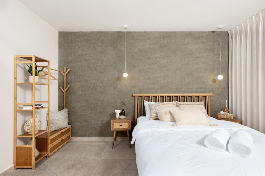 a bedroom with two beds and a gray wall at ארץ-נגב צימרים בירוחם in Yeroẖam