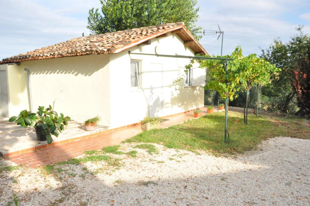 una pequeña casa blanca con un árbol en el patio en La Vite sul Tetto, en Agugliano