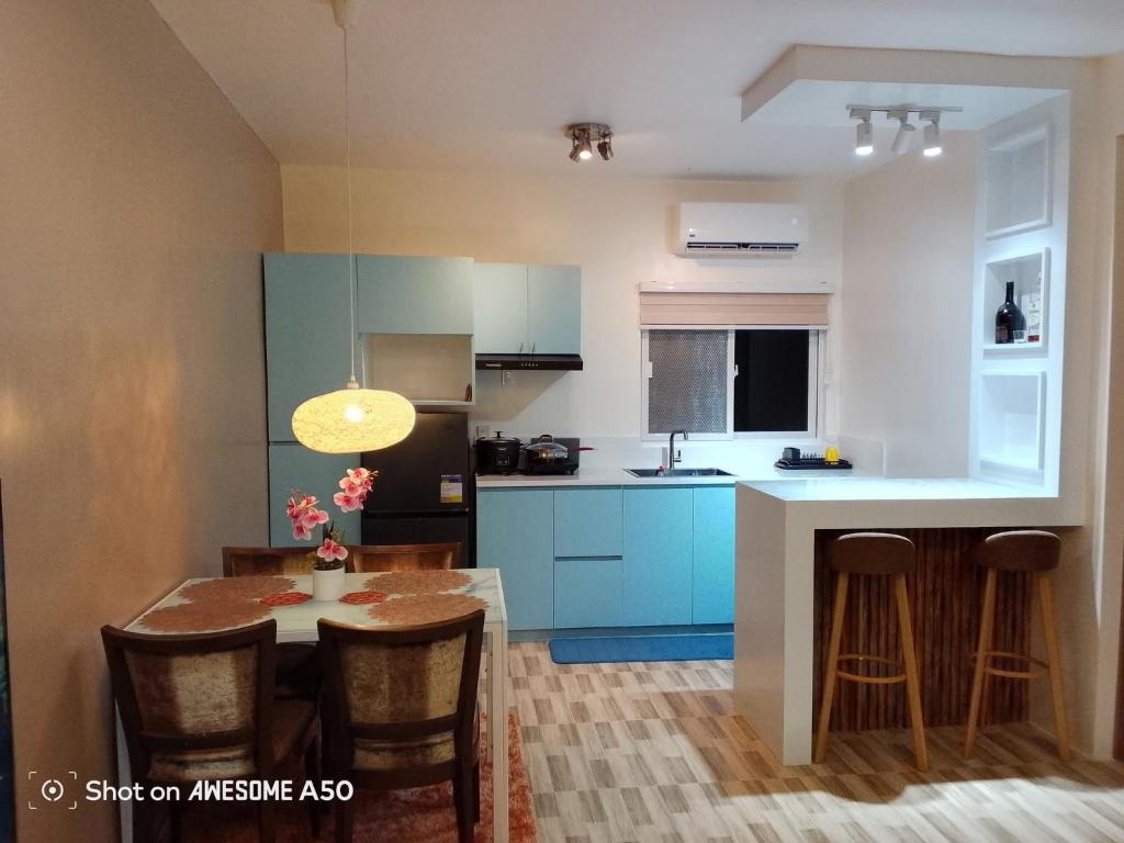 ジェネラル・サントスにあるHouse of Gabrielleの青いキャビネットとテーブルと椅子のあるキッチン