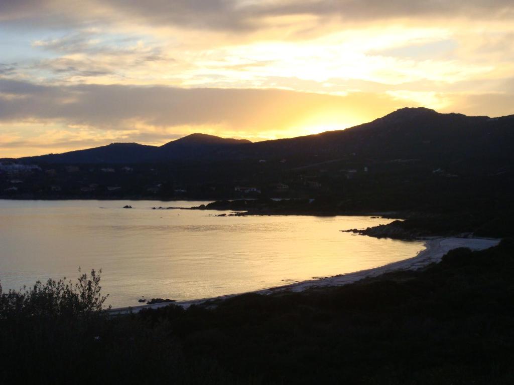 a sunset over a body of water with mountains at Appartamenti Spiaggia Bianca in Golfo Aranci