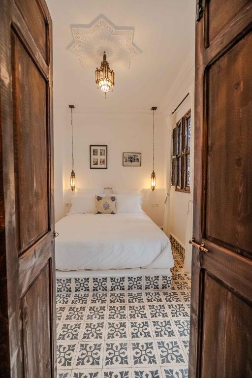 a bedroom with a bed and a chandelier at Riad Dar Irdide in Essaouira