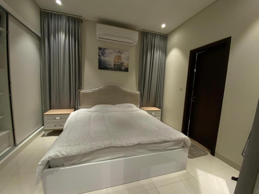 a bedroom with a white bed and two night stands at Hawana Salalah Tourism in Ma‘mūrah