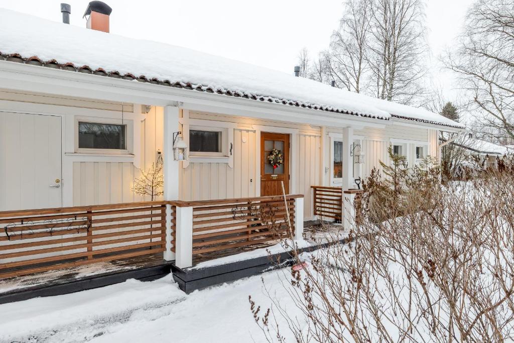 a white house with a porch in the snow at Rovaniemi Riverside Family House near Santa Claus Village - Sauna & Aurora View in Rovaniemi