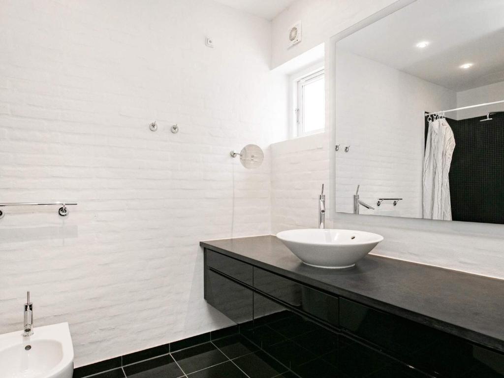 een witte badkamer met een wastafel en een spiegel bij 6 person holiday home in Skagen in Skagen